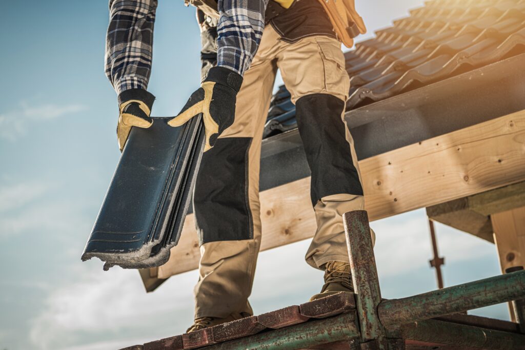 Bauindustrie. Dachdecker mit Keramikziegeln in den Händen. Nahaufnahme eines Dacharbeiters. Hausdachdeckung.