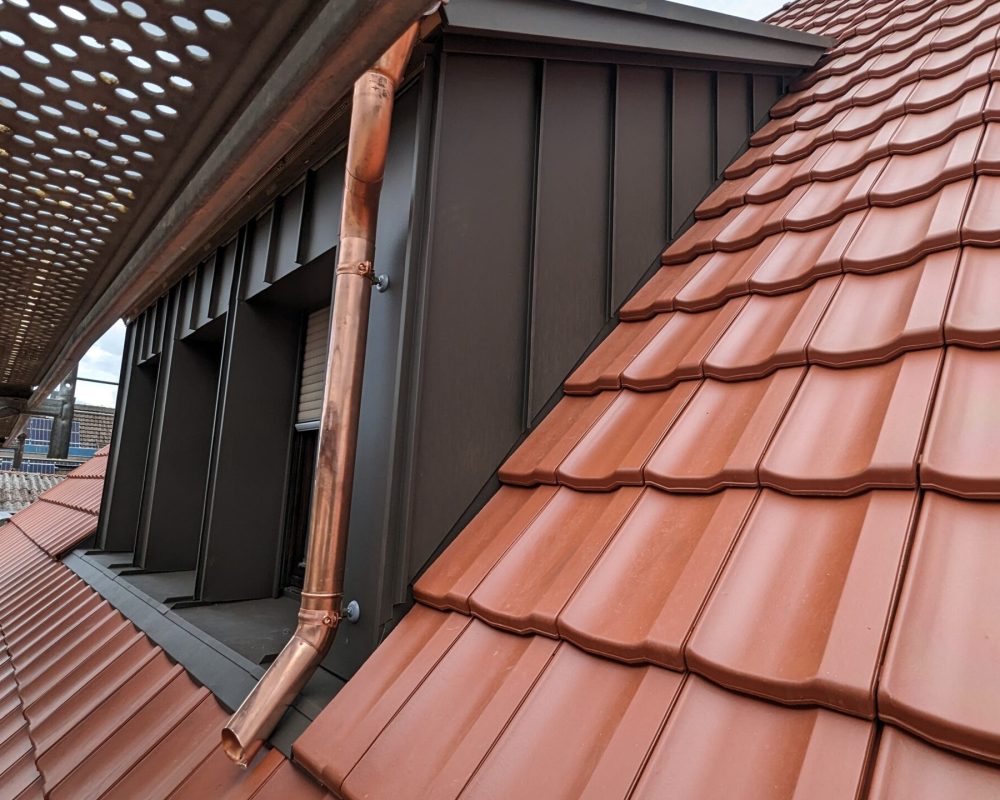 Nahaufnahme eines neuen roten Daches mit Kupferarbener Rinne