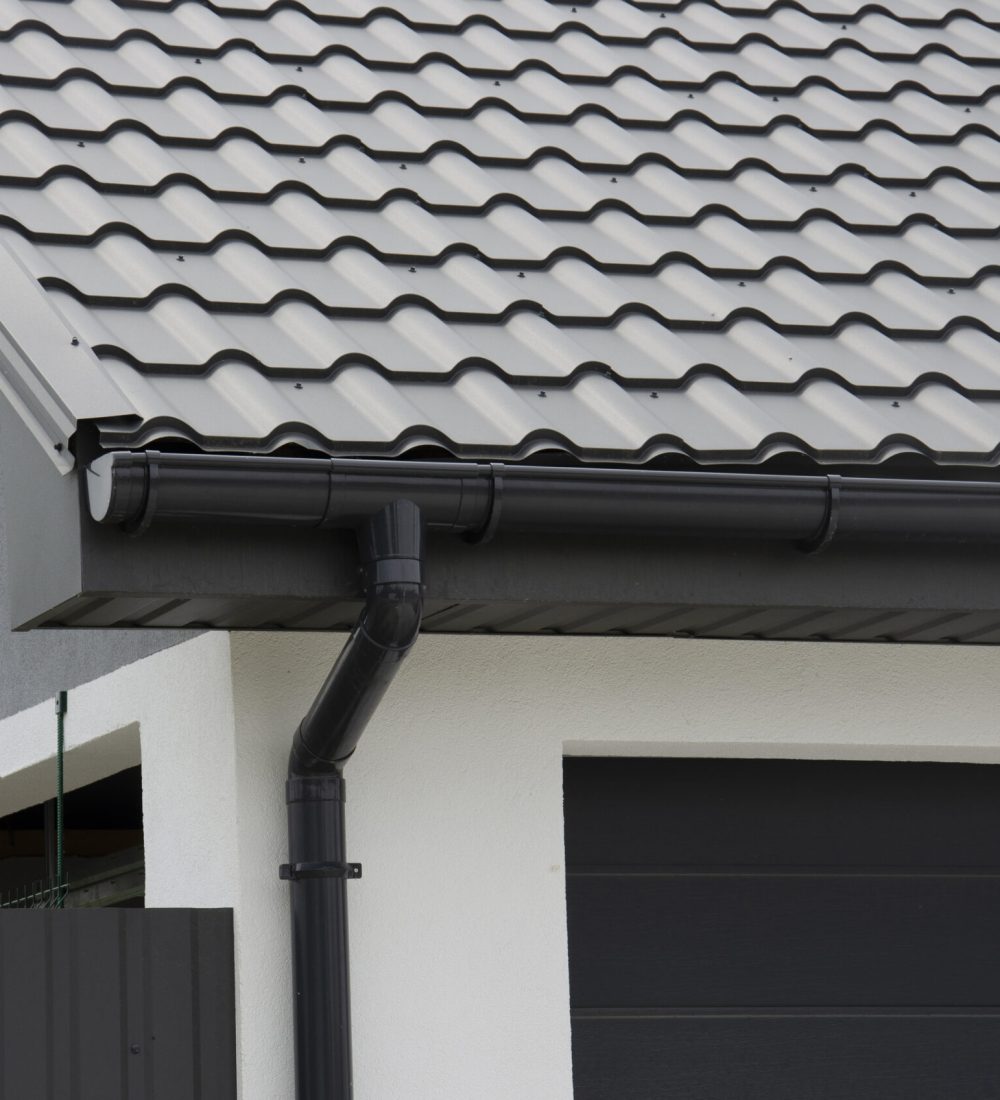 Schwarzes Kunststoff-Dachrinnensystem und Metallziegel auf dem Dach