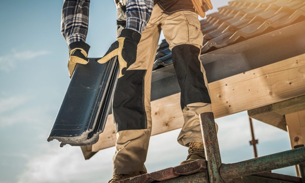 Bauindustrie. Dachdecker mit Keramikziegeln in den Händen. Nahaufnahme eines Dacharbeiters. Hausdachdeckung.